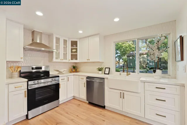 a kitchen with white cabinets appliances and a window