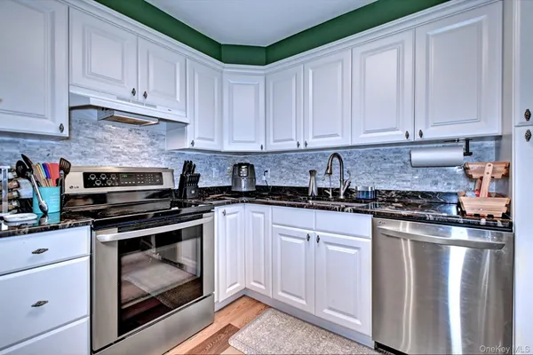 a kitchen with granite countertop white cabinets and stainless steel appliances