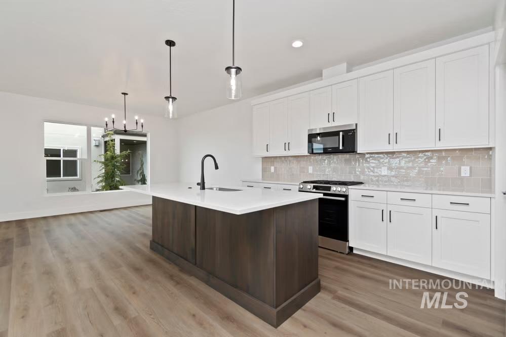 744 South Calhoun Lane Star, ID 83669 - Photo 34 of 34 Kitchen with a chandelier, a kitchen island with sink, open floor plan, white cabinets, and hanging light fixtures