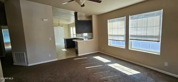 a view of an empty room with kitchen and a window