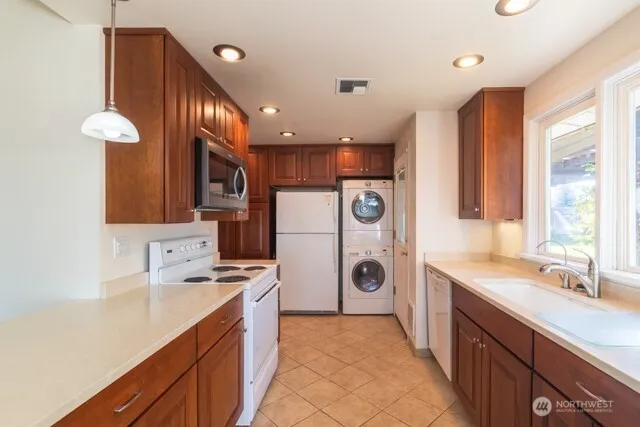 a kitchen with stainless steel appliances a sink a stove a refrigerator cabinets and a window