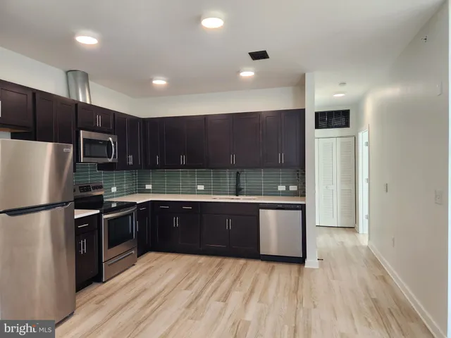 a kitchen with stainless steel appliances granite countertop a refrigerator a sink a stove and oven