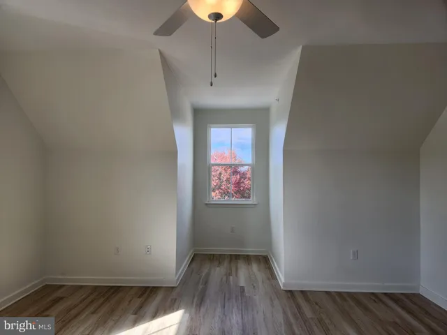 an empty room with wooden floor chandelier fan and windows