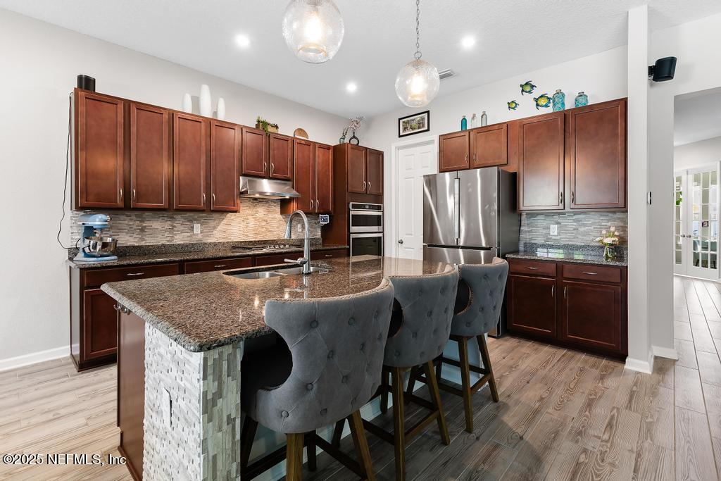 201 Oak Shadow Place St. Johns, FL 32259 - Photo 17 of 52 a kitchen with kitchen island granite countertop wooden cabinets and stainless steel appliances
