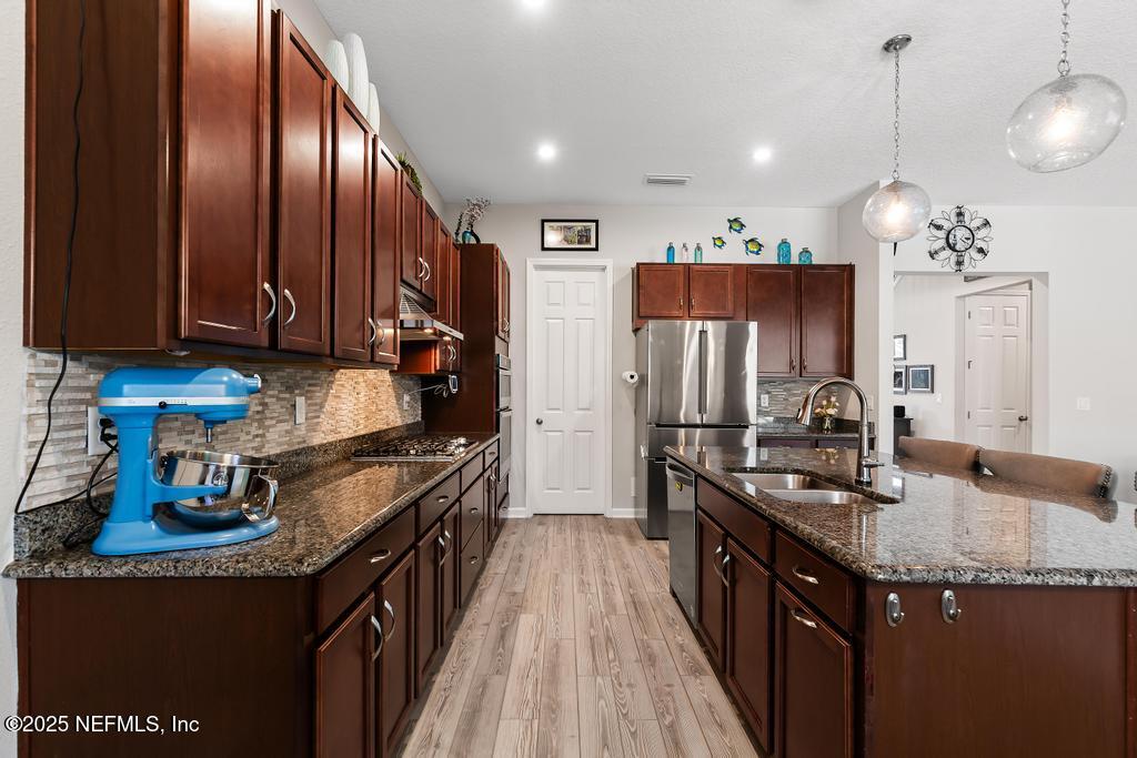 201 Oak Shadow Place St. Johns, FL 32259 - Photo 18 of 52 a kitchen with granite countertop wooden cabinets and stainless steel appliances