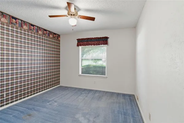 an empty room with windows and fan