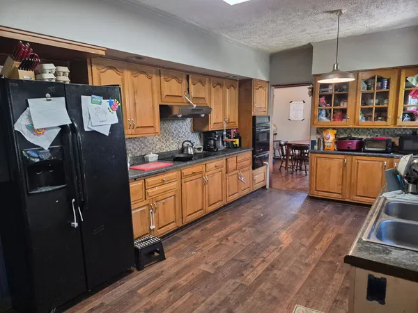 a kitchen with stainless steel appliances granite countertop a refrigerator a stove and a wooden floors