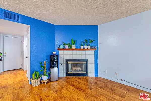 a view of an empty room with a fireplace and wooden floor