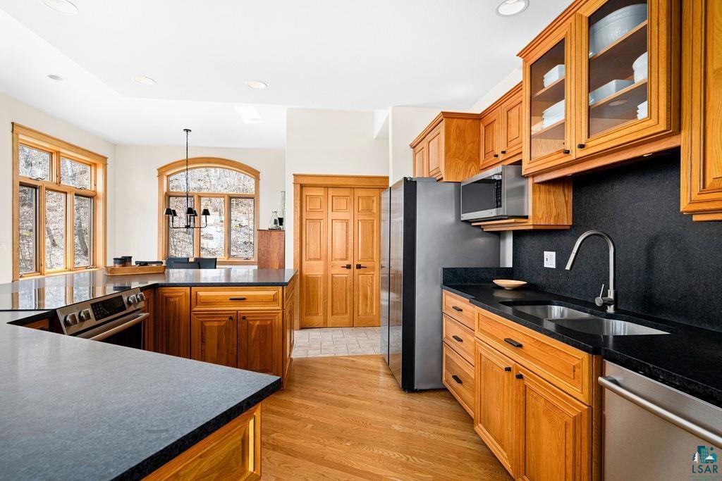 4856 Kingston Street Duluth, MN 55804 - Photo 15 of 88 Spacious kitchen featuring warm wood cabinetry, dark countertops, hardwood flooring, stainless steel appliances, and large windows with natural wood trim
