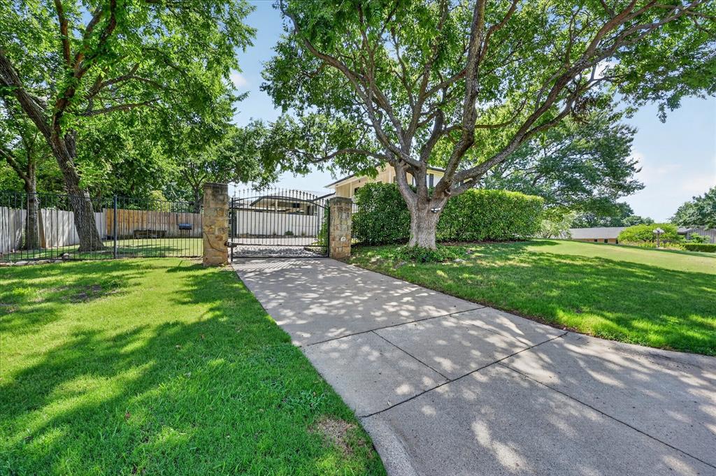 47 Bounty Road East Benbrook, TX 76132 - Photo 33 of 39 Concrete driveway accessing a wrought iron gate with stone pillar accents