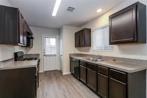 a kitchen with granite countertop stainless steel appliances a sink a stove top oven a counter space and cabinets