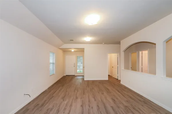 a view of a big room with wooden floor and kitchen view