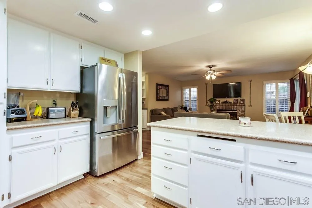 13919 Poway Valley Road Poway, CA 92064 - Photo 29 of 70 a kitchen with stainless steel appliances granite countertop a refrigerator a stove and white cabinets with wooden floors