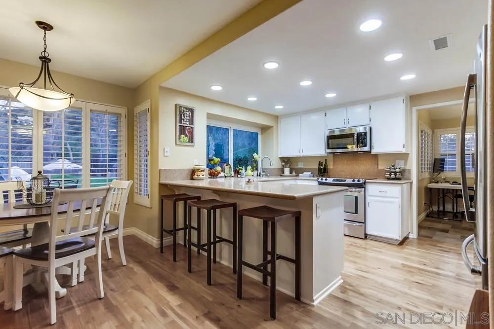 13919 Poway Valley Road Poway, CA 92064 - Photo 31 of 70 a kitchen with stainless steel appliances granite countertop a stove a sink dishwasher a dining table and chairs with wooden floor