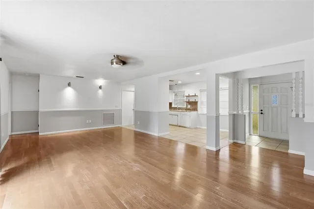 a view of an empty room with wooden floor and a window