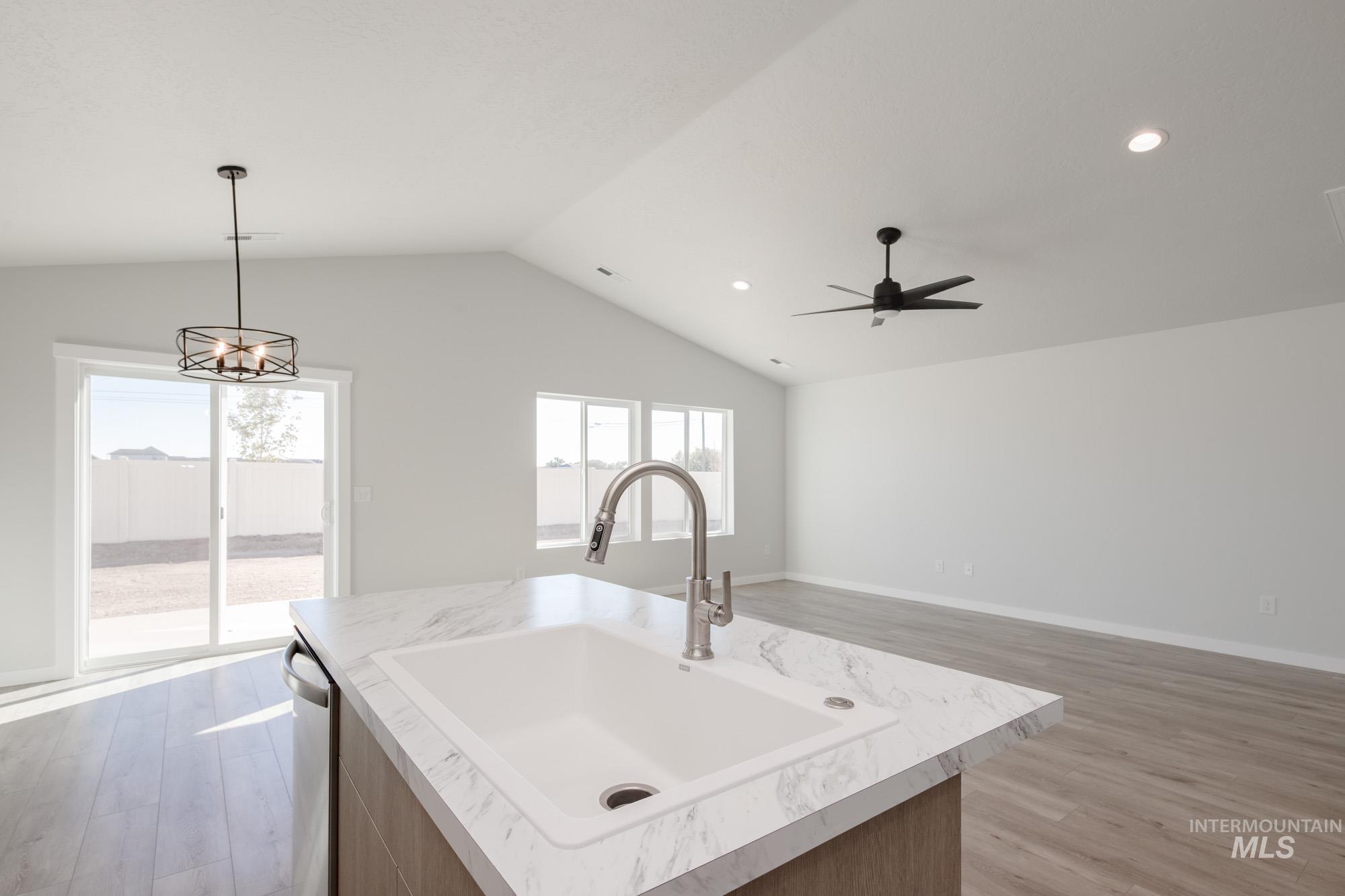 13735 Inman Court Caldwell, ID 83607 - Photo 21 of 22 Kitchen with light wood-style flooring, light countertops, open floor plan, hanging light fixtures, and a kitchen island with sink