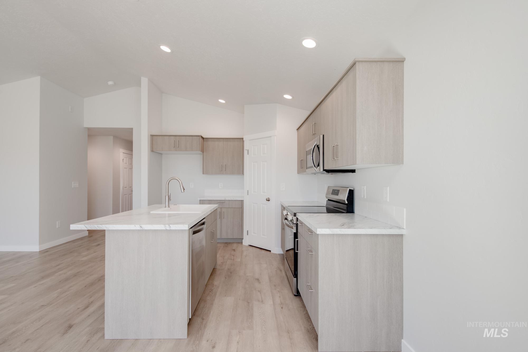 13735 Inman Court Caldwell, ID 83607 - Photo 8 of 22 Kitchen with light wood finish cabinetry, stainless steel appliances, modern cabinets, a center island with sink, and lofted ceiling