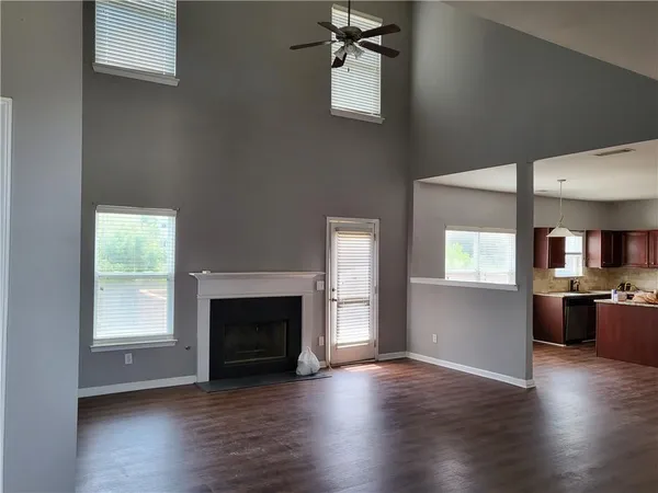 an empty room with wooden floor fireplace and windows