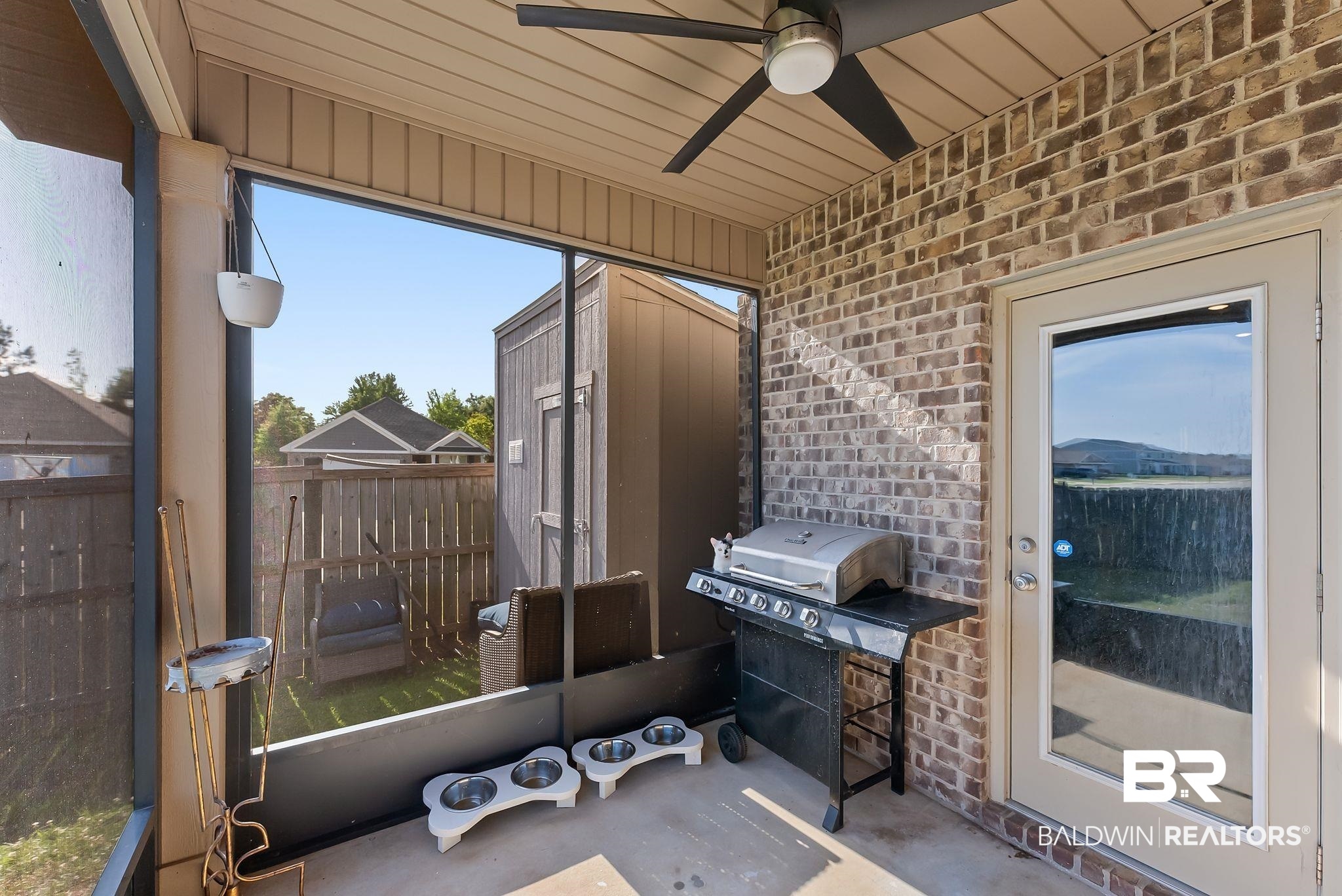 16607 Prado Loop Loxley, AL 36551 - Photo 40 of 46 Screened patio featuring a ceiling fan, brick wall, concrete flooring, and an exterior door with a full-light panel