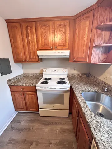 a kitchen with granite countertop a sink stove and cabinets