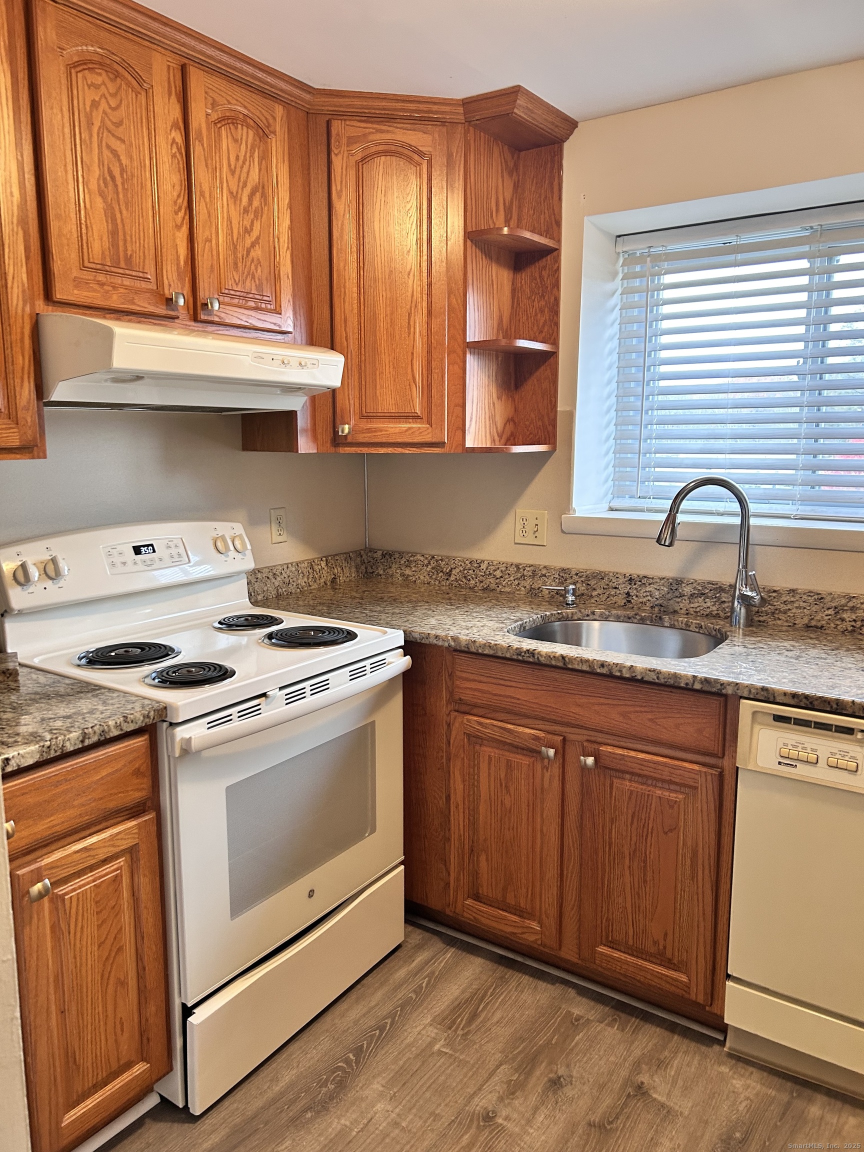 4 Carillon Drive, Unit B Rocky Hill, CT 06067 - Photo 6 of 16 a kitchen with granite countertop a stove a sink and dishwasher wooden cabinets with wooden floor