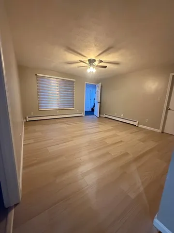 a view of an empty room with window and wooden floor
