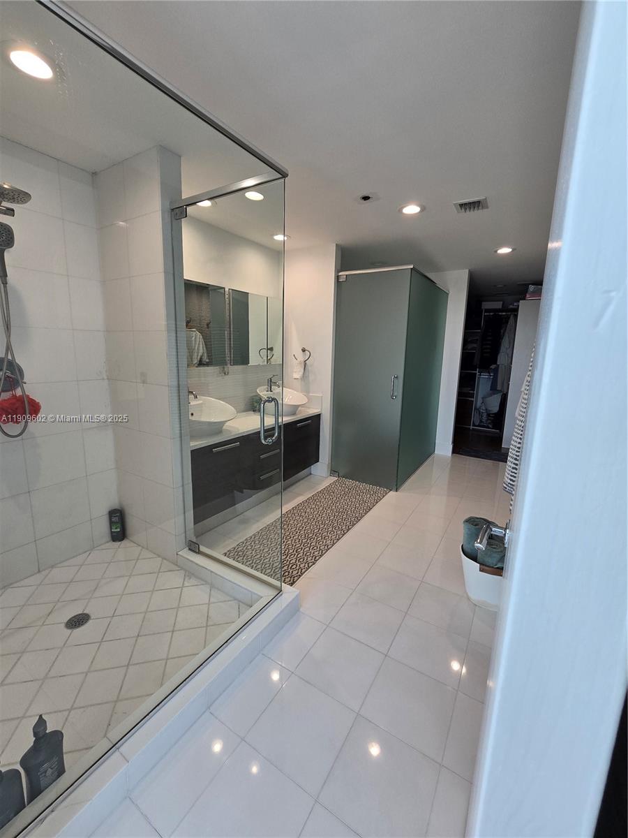 2950 Northeast 188th Street, Unit 501 Aventura, FL 33180 - Photo 36 of 46 a bathroom with a sink a mirror and a shower