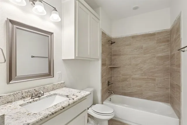 a bathroom with a granite countertop sink a toilet and shower