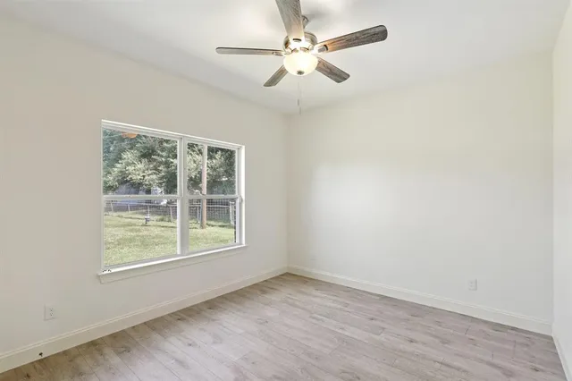 an empty room with a window and a fan