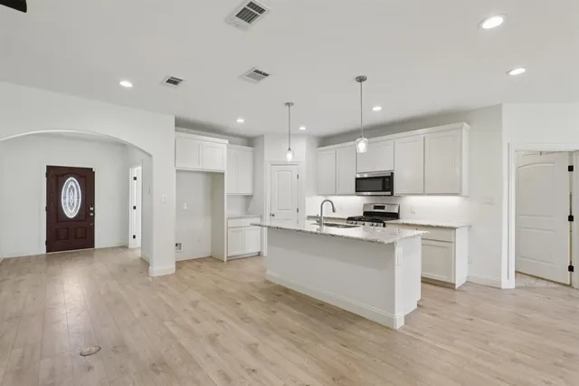 a kitchen with white cabinets and stainless steel appliances