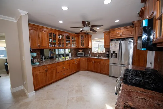 a kitchen with stainless steel appliances granite countertop a refrigerator a sink a stove and cabinets
