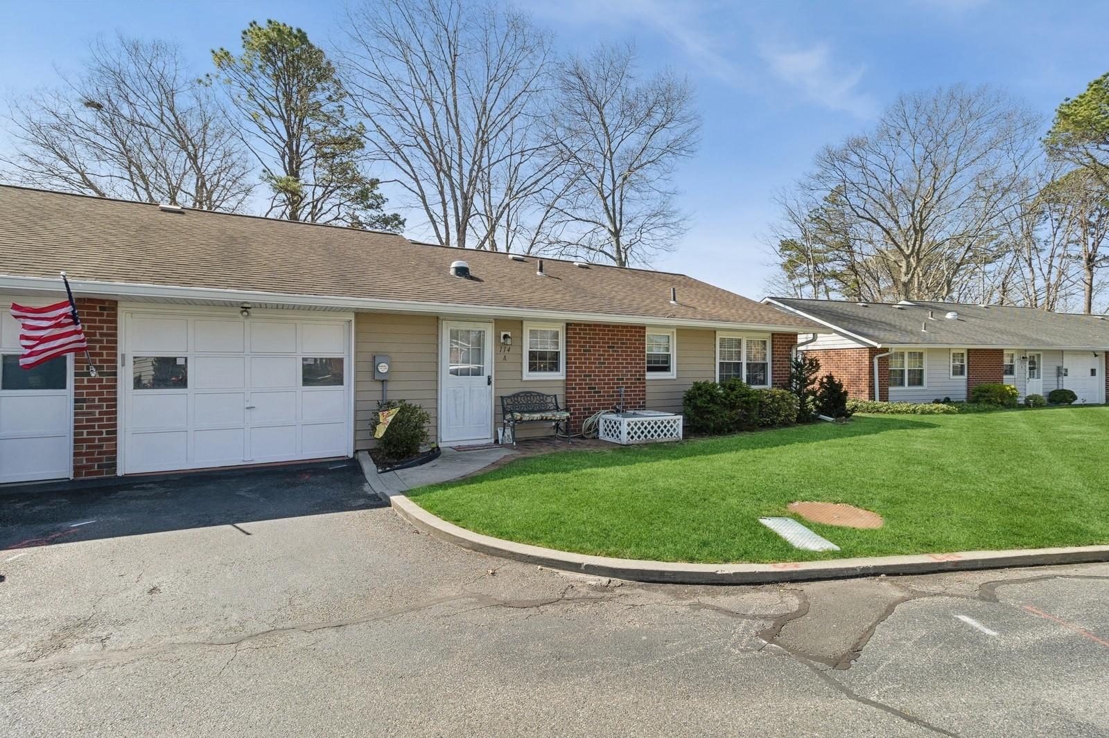 114 Exmore Court, Unit A Ridge, NY 11961 - Photo 1 of 1 a view of a white house in front of a yard with plants and large trees