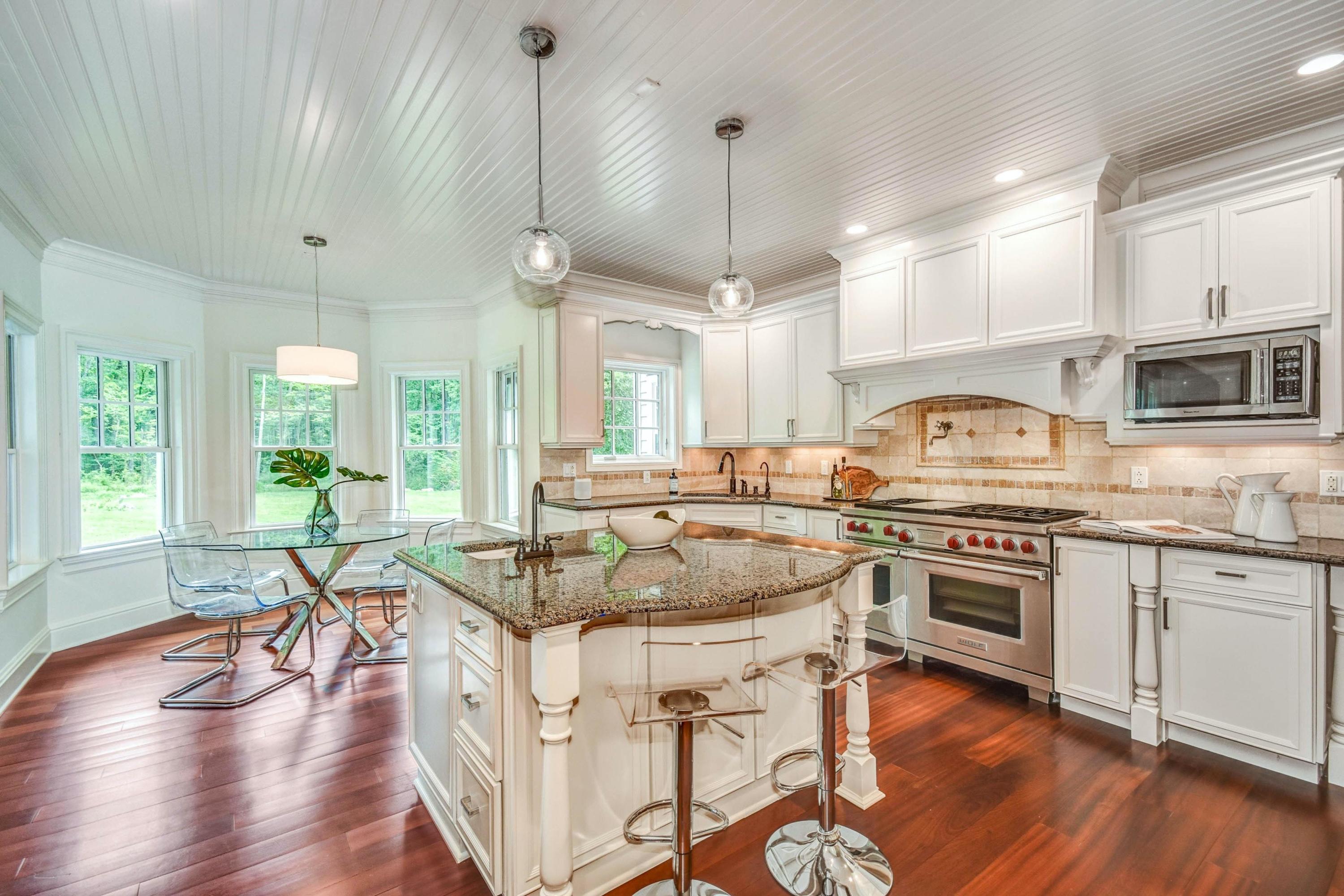 56 Logan Road New Canaan, CT 06840 - Photo 12 of 40 a kitchen with stainless steel appliances granite countertop a stove top oven a sink a stove and white cabinets with wooden floor