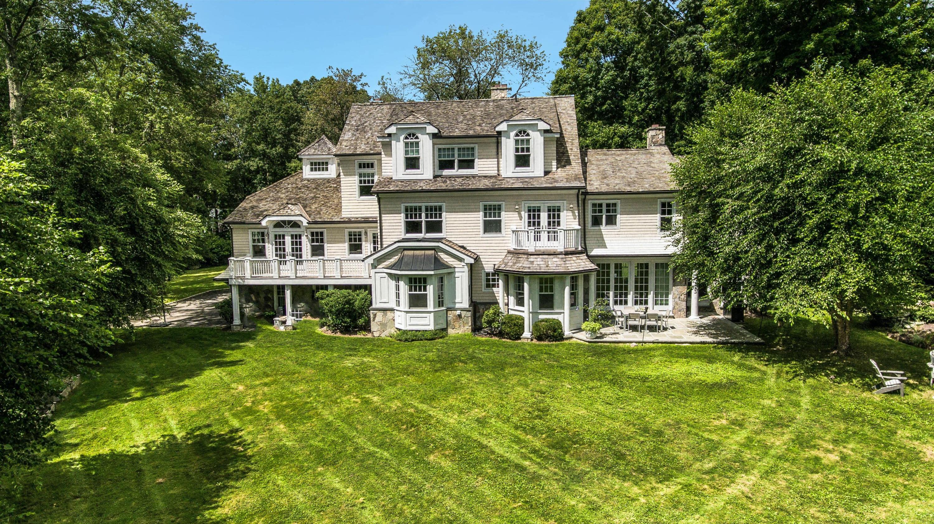 56 Logan Road New Canaan, CT 06840 - Photo 36 of 40 a view of a white house with a big yard and potted plants and large trees