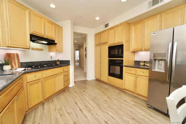 a kitchen with stainless steel appliances granite countertop a refrigerator and a stove top oven