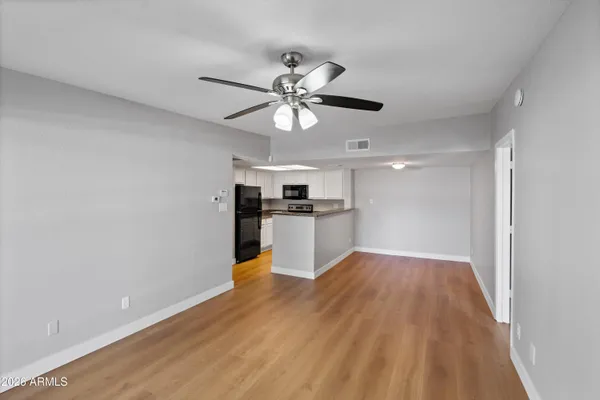 a view of an empty room with a kitchen and a window