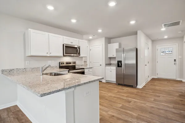 a kitchen with stainless steel appliances granite countertop a sink a refrigerator and a granite counter tops