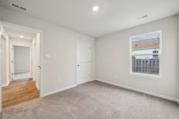 a view of a hallway with wooden floor and a bathroom