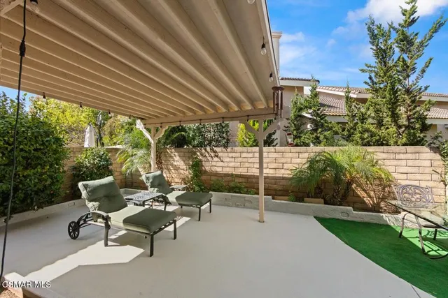 a view of a patio with table and chairs under an umbrella with a garden