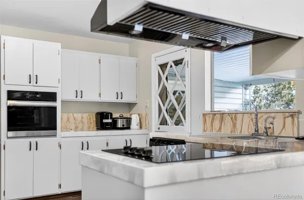 a kitchen with granite countertop a stove a sink and a white cabinets