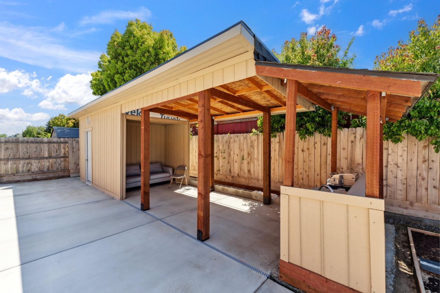 264 Rosebriar Street Madera, CA 93638 - Photo 26 of 28 a view of a patio with a table and chairs under an umbrella with wooden fence