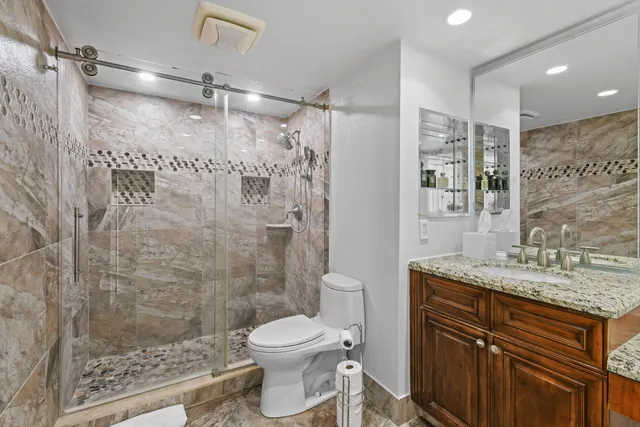 a bathroom with a granite countertop sink toilet and shower