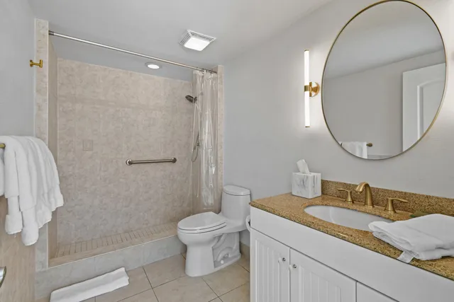 a bathroom with a granite countertop sink a mirror a toilet and a shower