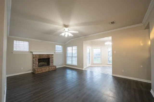 an empty room with wooden floor fireplace and windows
