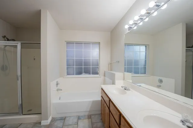 a bathroom with a sink double vanity granite tub shower and a mirror