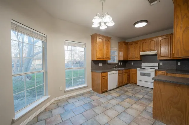 a kitchen with a stove a sink cabinets and a window
