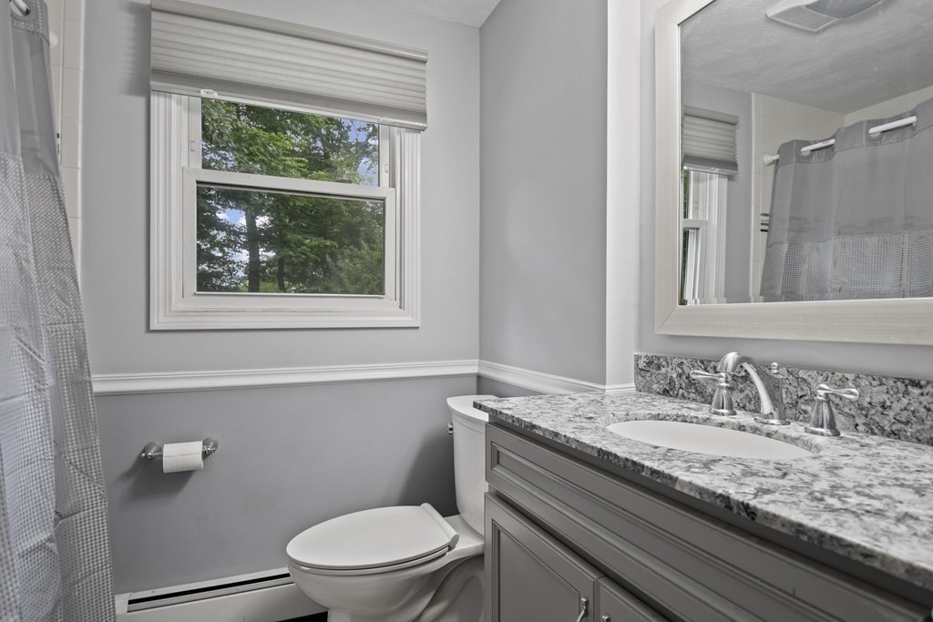 14 Porter Street Billerica, MA 01821 - Photo 17 of 33 a bathroom with a granite countertop toilet a sink a mirror and a window