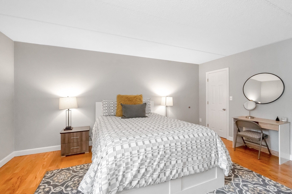 159 Main Street, Unit 15B Stoneham, MA 02176 - Photo 13 of 25 a bedroom with a bed a mirror and lamp