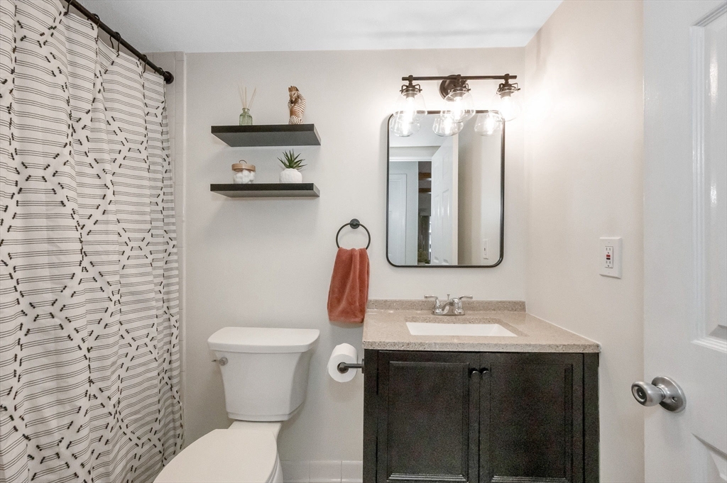 159 Main Street, Unit 15B Stoneham, MA 02176 - Photo 16 of 25 a bathroom with a granite countertop toilet sink and mirror