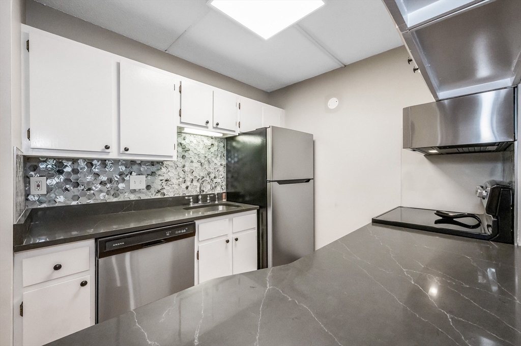 159 Main Street, Unit 15B Stoneham, MA 02176 - Photo 2 of 25 a kitchen with granite countertop a sink stove and refrigerator
